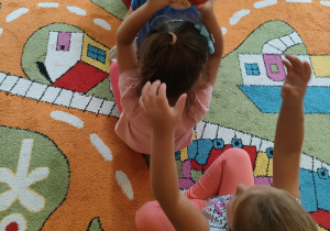 Dziewczynka podaje nad głową koleżance dynie.