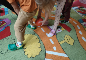 Dzieci podają sobie dynie między nogami.