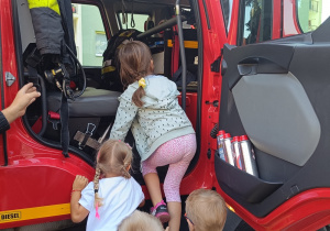 Dzieci wchodzą do wozu strażackiego.