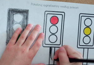 Dziecko koloruje sylwetę sygnalizatora świetlnego.