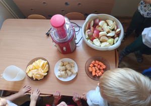 Dzieci przy stole z owocami i sokowirówką