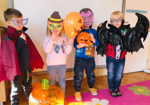 Przebrane dzieci stoją w Sali i pozują do zdjęcia w strojach halloween’owych.