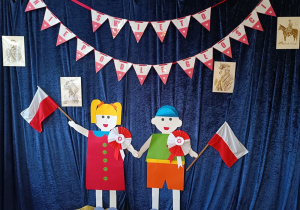 Dekoracja z okazji Święta Niepodległości - chłopiec i dziewczynka trzymają w rączkach flagi Polski.