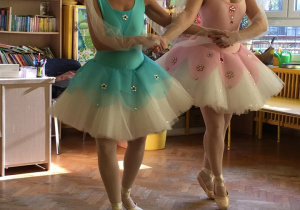 Dwie baletnice trzymają się za ręce, prezentują taniec.