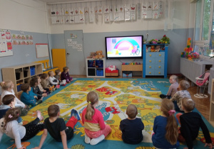 Przedszkolaki oglądają na monitorze multimedialnym film edukacyjny o prawach dzieci.