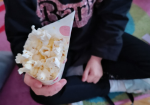 Dziecko trzyma w rączce popcorn.
