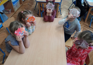Dzieci trzymają w rączkach pokolorowane misie origami.