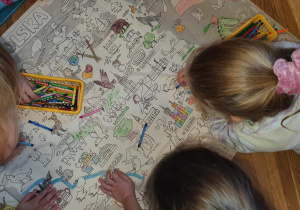 Dzieci kolorują dużą kolorowankę przedstawiającą mapę Polski.