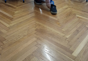 Dziecko przekłada buty jeden za drugim w kierunku drzwi.