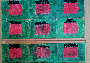 Prace dzieci wywieszone na tablicy - czerwone wagony z węglem na zielonym tle.