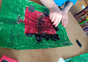 Chłopiec maluje węglem wagonik.