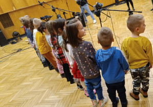 Dzieci stoją przed mikrofonami.