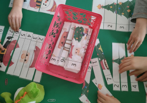 Przedszkolaki układają puzzle z obrazkami świątecznymi.
