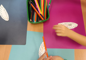 Dzieci kolorują pióra do wspólnego plakatu.