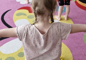 Dziewczynki stoją na dywanie z woreczkami na głowie.