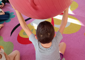 Chłopiec trzyma uniesioną dużą piłkę.