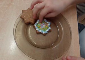 Dziecko dekoruje korzenne ciasteczko cukrowymi ozdobami.