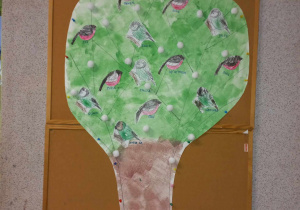 Na tablicy wywieszone drzewo z pokolorowanymi przez dziećmi ptakami.