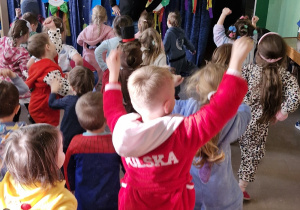 Dzieci tańczą - powtarzają ruchy za mężczyzną stojącym na środku.