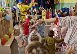 Dzieci i nauczyciele tańczą do muzyki podnosząc ręce do góry.