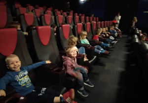 Dzieci zajmują cały rząd miejsc w Sali kinowej i czekają na projekcje filmu.