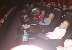 Dzieci siedzą w sali kinowej zadowolone po projekcji filmu.