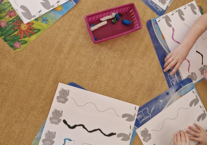 Dzieci z wykorzystaniem plasteliny wyklejają drogę żabek do listka.