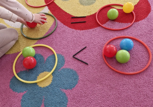 Dziecko układa kolorowe piłeczki po dwóch stronach symbolu równości.