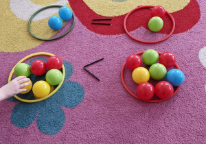 Dziecko układa kolorowe piłeczki po dwóch stronach symbolu mniejszości.
