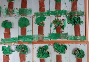 Prace dzieci wywieszone na tablicy: drzewa wykonane z surowców wtórnych- foli bąbelkowej, rolki po papierze, gazety.