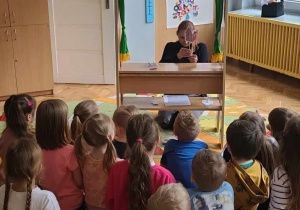 Nauczycielka pokazuje dzieciom kukiełki z przedstawienia ,,Trzy świnki''.