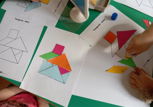 Chłopiec układa z figur geometrycznych domek.