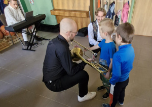 Dzieci z bliska oglądają instrument muzyczny: puzon.