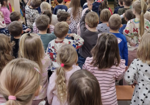 Dzieci powtarzają ruchy za muzykiem, który znajduje się na scenie.