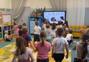 Dzieci w strojach do gimnastyki wykonują ćwiczenia.