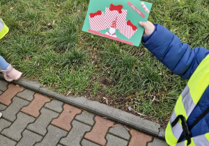 Chłopiec podczas spaceru trzyma w ręce i pokazuje kartkę świąteczną.