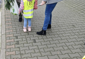 Dziewczynka wręcza spotkanej kobiecie kartkę świąteczną.