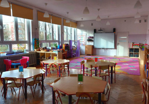 Sala grupy fioletowej - stoliki przy których stoją krzesełka, fioletowy dywan w motyle, szafki, na których poukładane są zabawki
