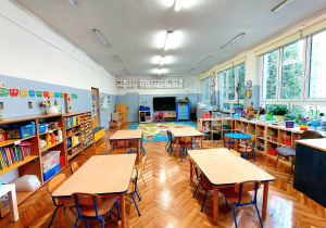 Sala grupy niebieskiej - stoliki przy których stoją krzesełka, szafki z zabawkami, monitor multimedialny na ścianie, na podłodze dywan