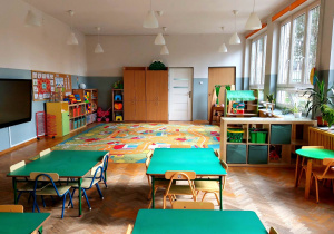 Sala grupy zielonej - stoliki przy których stoją krzesełka, dywan z motywem drogi, szafki, na których poukładane są zabawki
